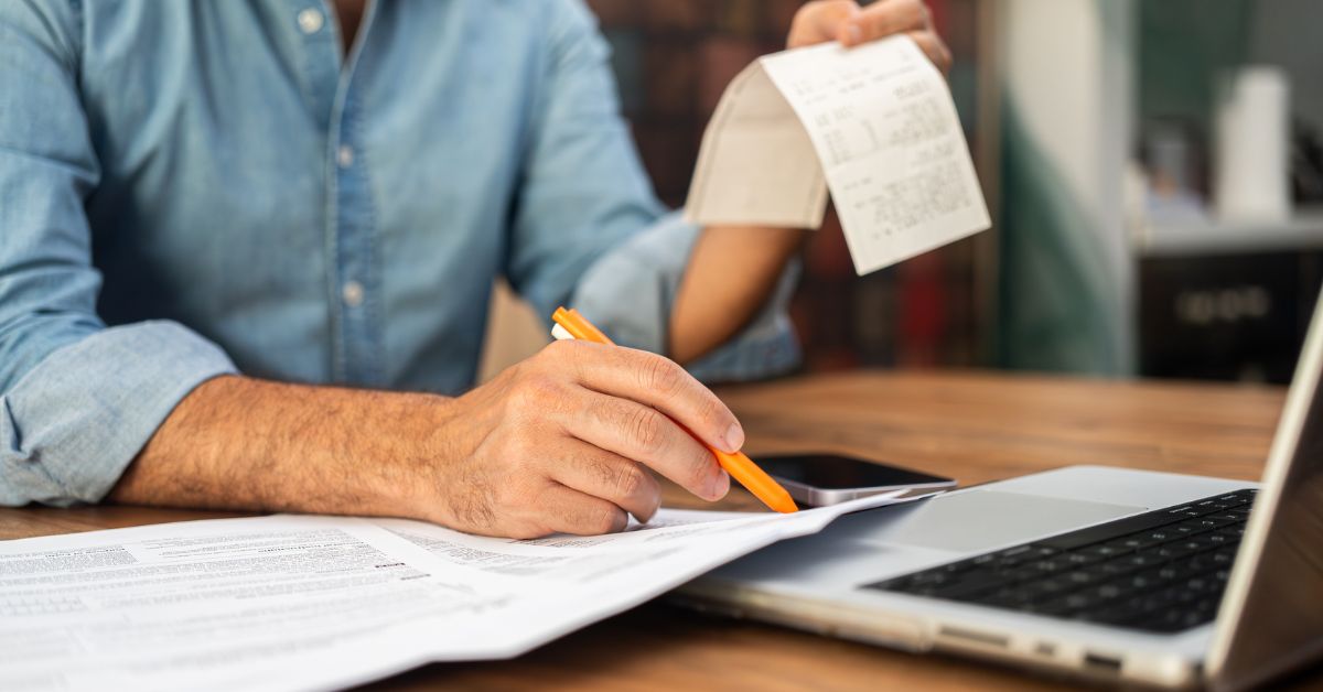 Someone jotting down numbers and looking at a receipt.